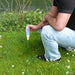 Person using a water quality meter in a grassy area near a body of water.