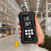 Hand holding a digital hygrometer in a warehouse setting