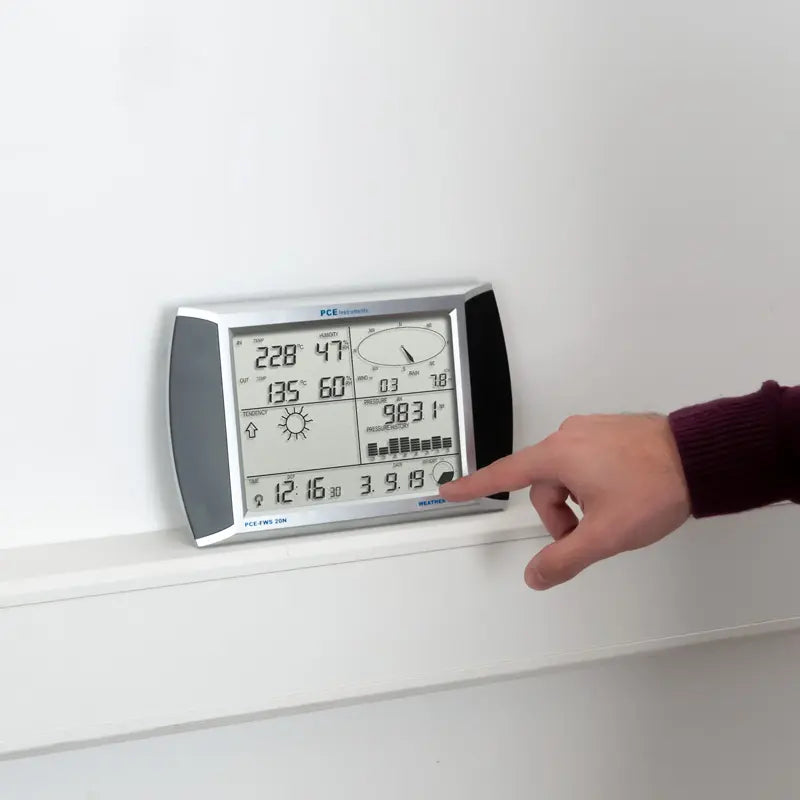 Hand interacting with a digital weather station on a white wall