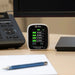 Air quality meter on a desk with a computer monitor and phone in the background
