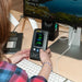 Person using a digital device on a desk with computer monitors in the background