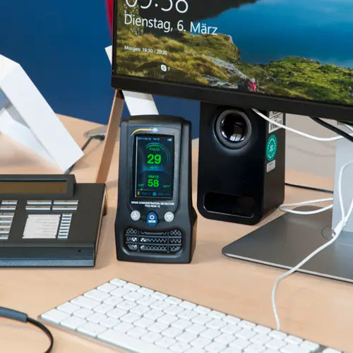Desk setup with computer monitor, keyboard, and digital thermometer on a desk.