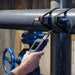 Person using a Ultrasonic Flow Meter to check pressure on a pipe with a blue valve.