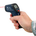 Hand holding a PCF infrared thermometer against a white background