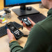 Person using a light meter on a desk with a computer monitor in the background