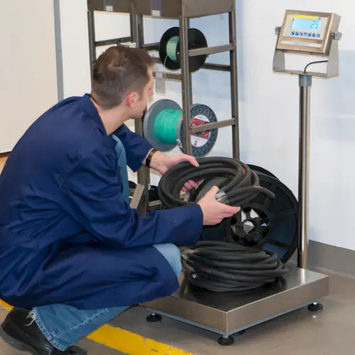 Person working with coiled cable on a weighing scale in a controlled environment