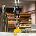 Digital hanging scale with a yellow hook in an industrial setting