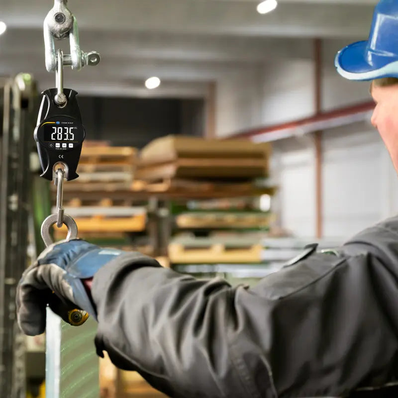 Person using a digital hanging scale in a warehouse setting