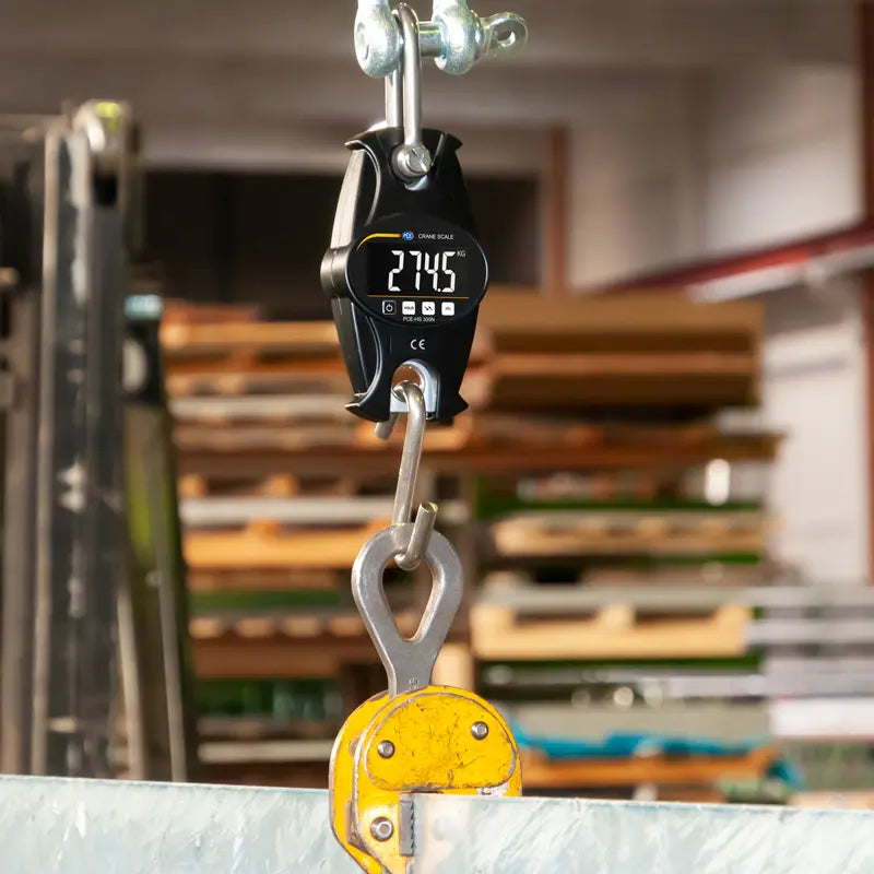 Digital hanging scale with a hook in a warehouse setting