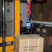 Cardboard box being weighed on a forklift scale in a warehouse.