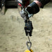 Digital hanging scale with a hook being held by gloved hands on a blurred background