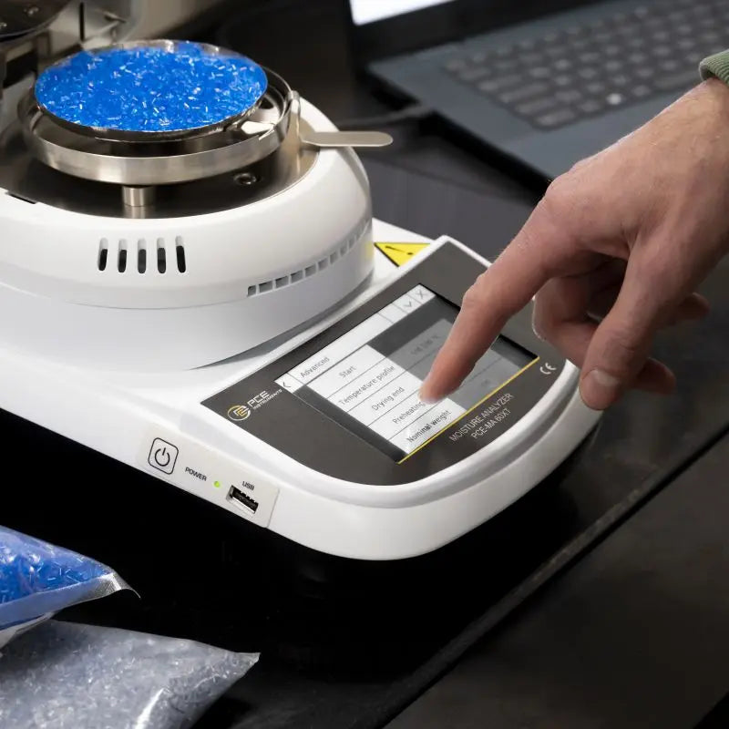 Person interacting with a moisture analyzer on a lab bench