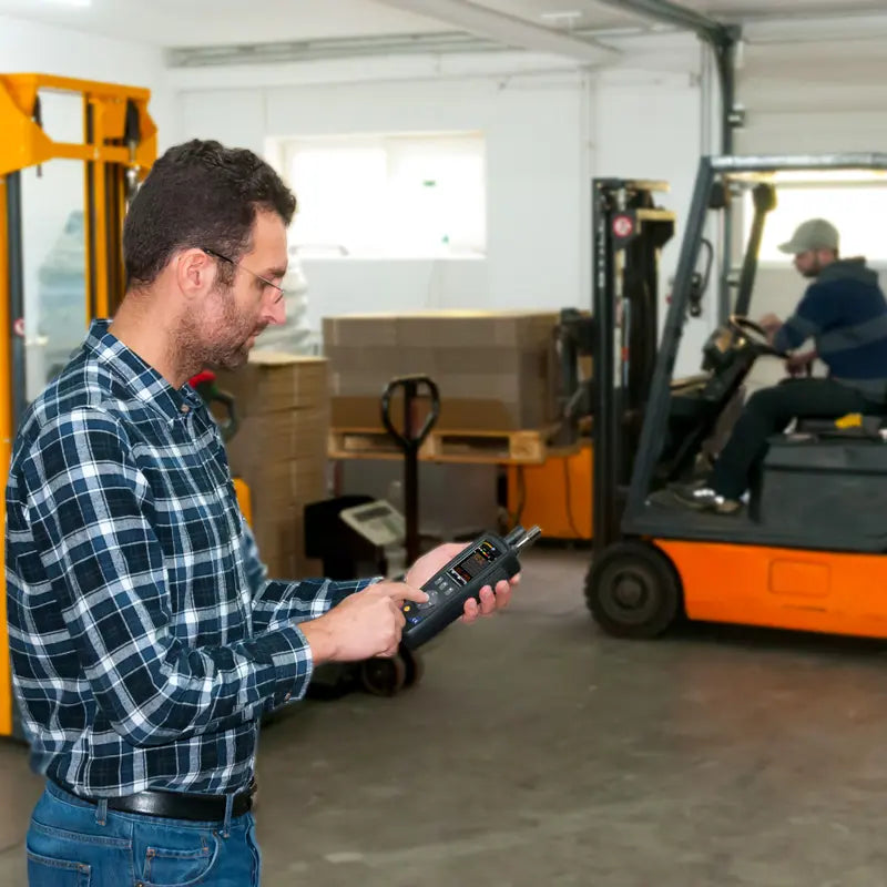 Man operating a forklift with a Particle counter in a warehouse setting