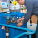 Person working on a blue industrial machine with various components.