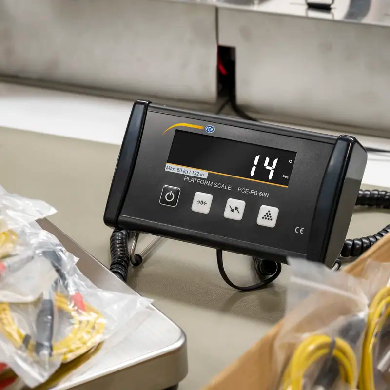 Digital display on a platform scale with food items in the background