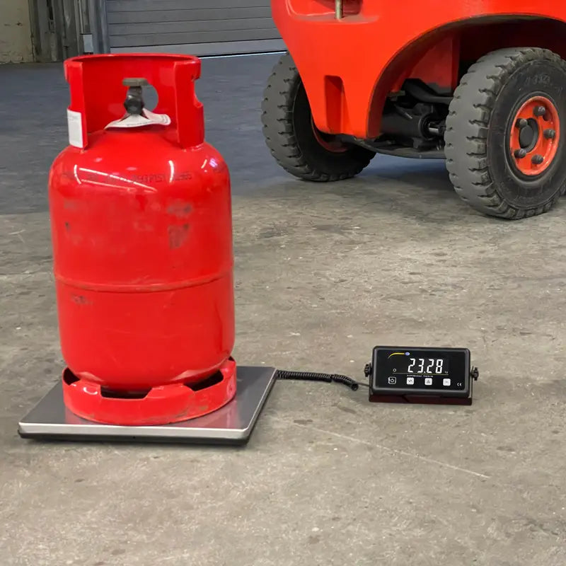 Red propane tank on a scale with a digital display in an industrial setting