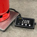 Digital scale displaying weight next to a red container on a concrete floor