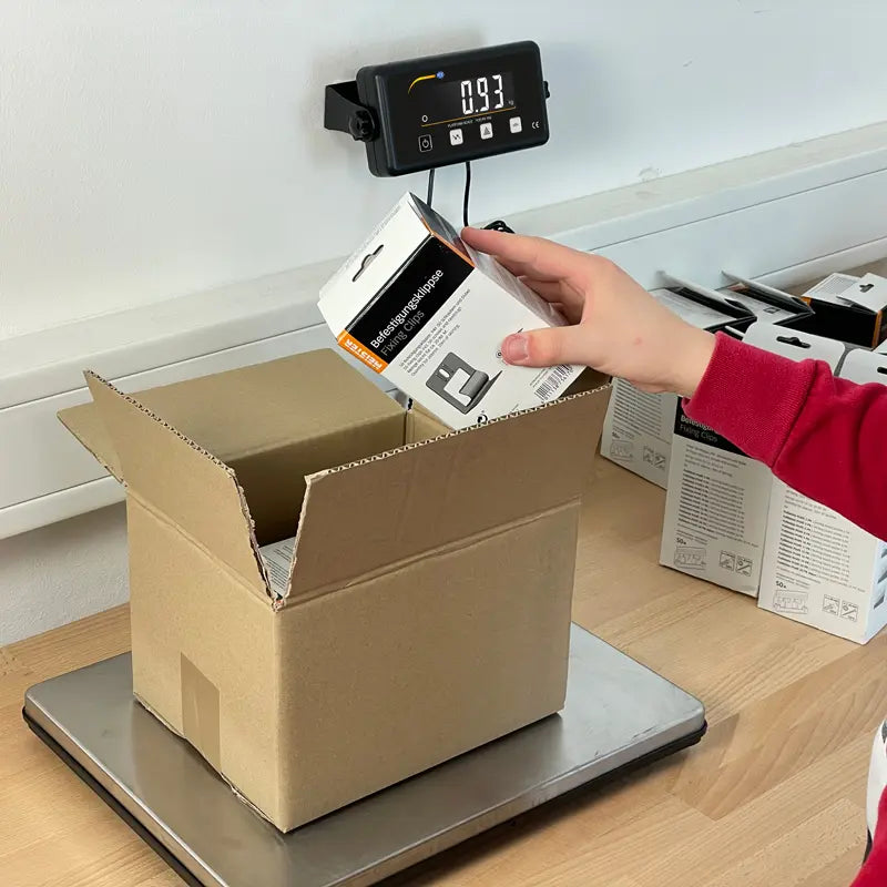 Person placing a box on a digital scale with a white background