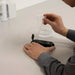 Person using a refractometer with a clear container on a white surface