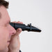 Person using a refractometer near their mouth on a white background