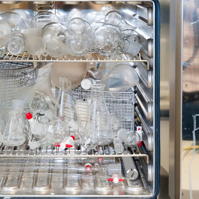 Open dishwasher with clean glassware and cutlery inside