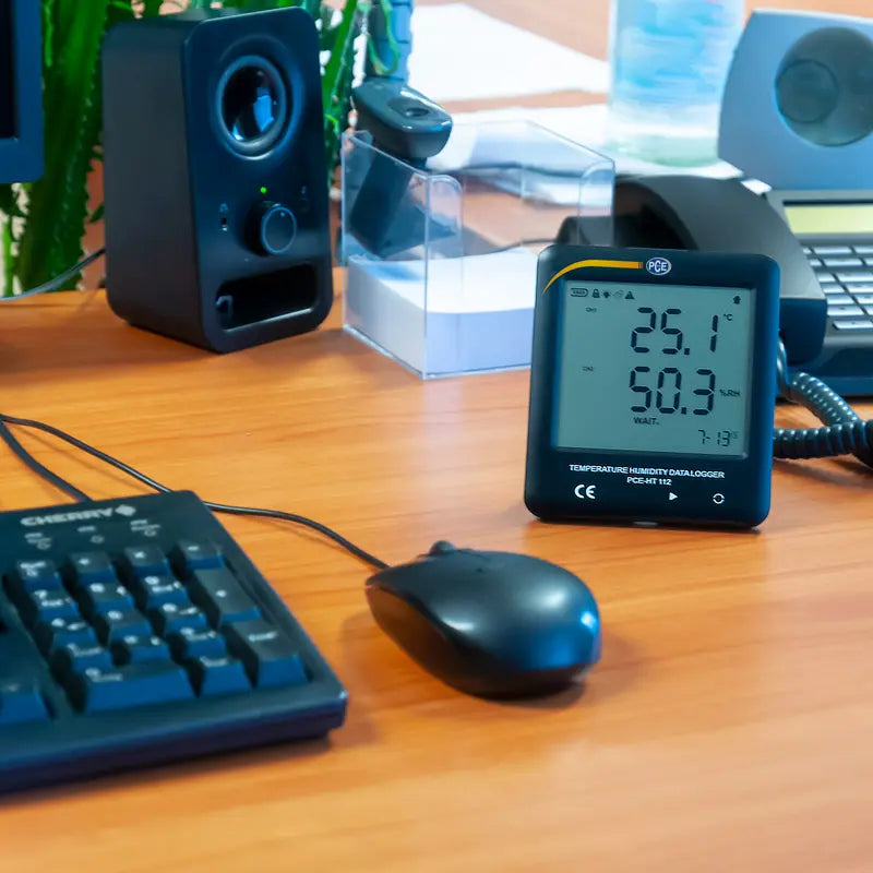 Digital thermometer on a desk with computer equipment