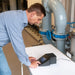 Man using a Turbidity Meter near industrial pipes and equipment.