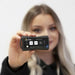 Person holding a Vibration Meter with a visible brand logo against a plain background