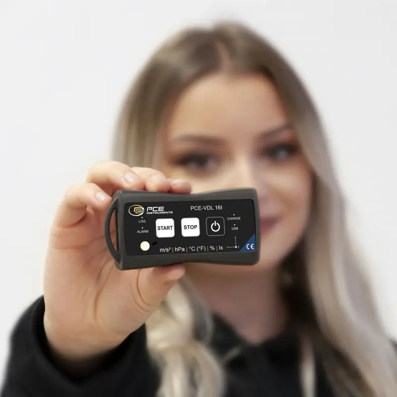 Person holding a Vibration Meter with a visible brand logo against a plain background