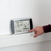 Hand interacting with a digital weather station on a white wall