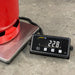 Digital scale with a red container on it, displaying weight on a concrete floor.