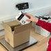 Person placing a box on a digital scale with a white background